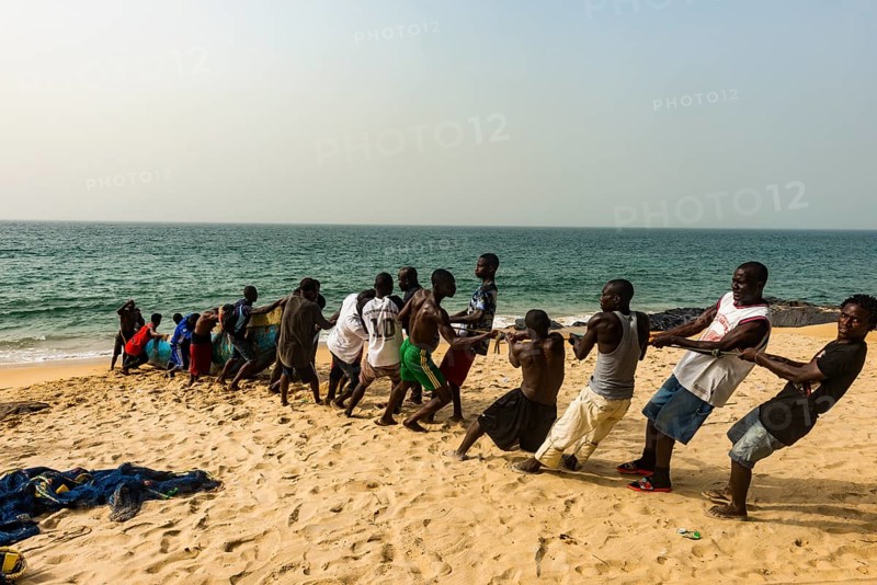 Local fishermen pulling their nets on a beach in Robertsport