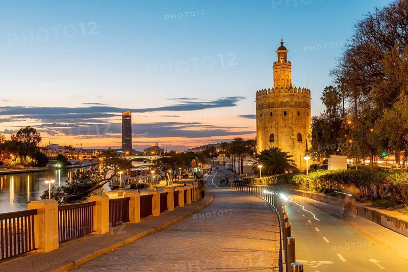 Boardwalk at the river Rio Guadalquivir with illuminated Torre del Oro