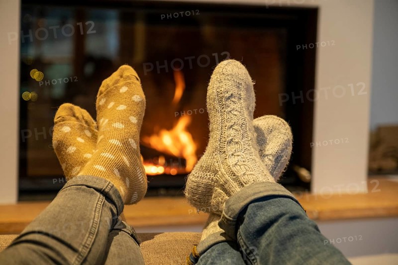 Feet with cuddly socks in front of a fireplace