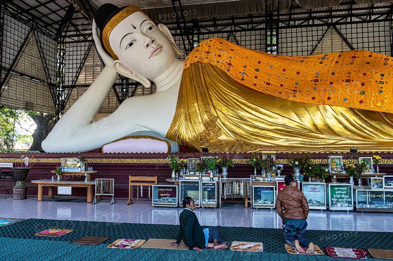 Pilgrims praying before a reclining buddha