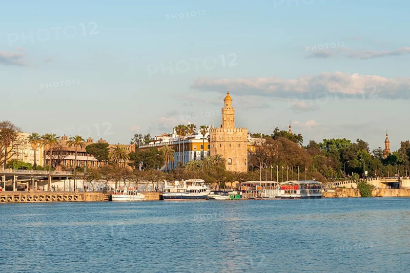 View over the river Rio Guadalquivir on promenade with excursion boats and Torre del Oro