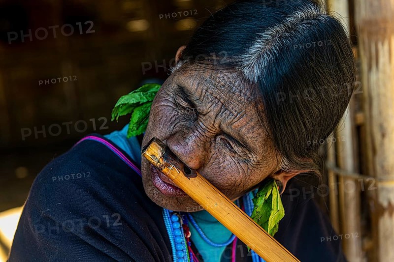 Chin woman with spiderweb tattoo blowing a flute with her nose
