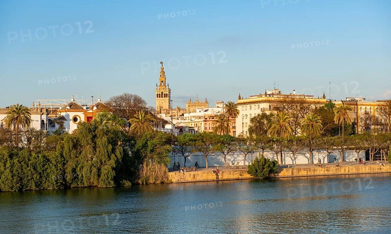 View over the river Rio Guadalquivir to the bullring Plaza de toros de la Real Maestranza de Caballeria de Sevilla and bell tower La Giralda