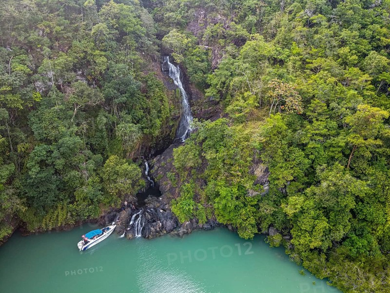 Aerial of a waterfall dropping right in the ocean on Dome island