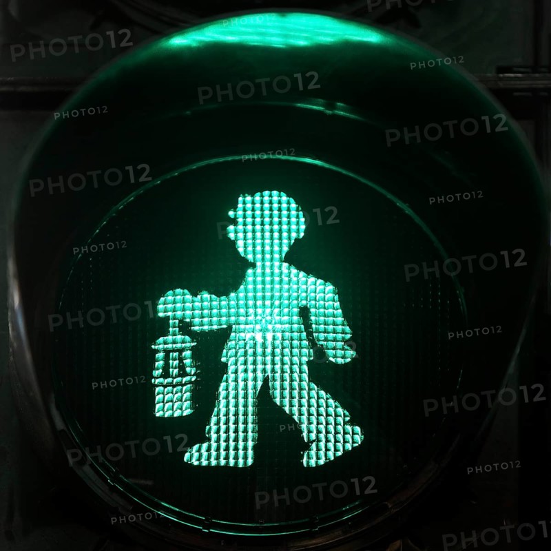 Green pedestrian traffic light man as miner with pit lamp