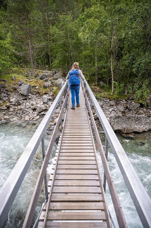 Hiker on wooden bridge over the river Driva