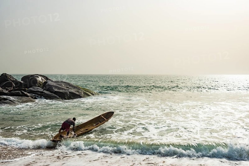 Man mounts his dugout canoe on the ocean east of Buchanan
