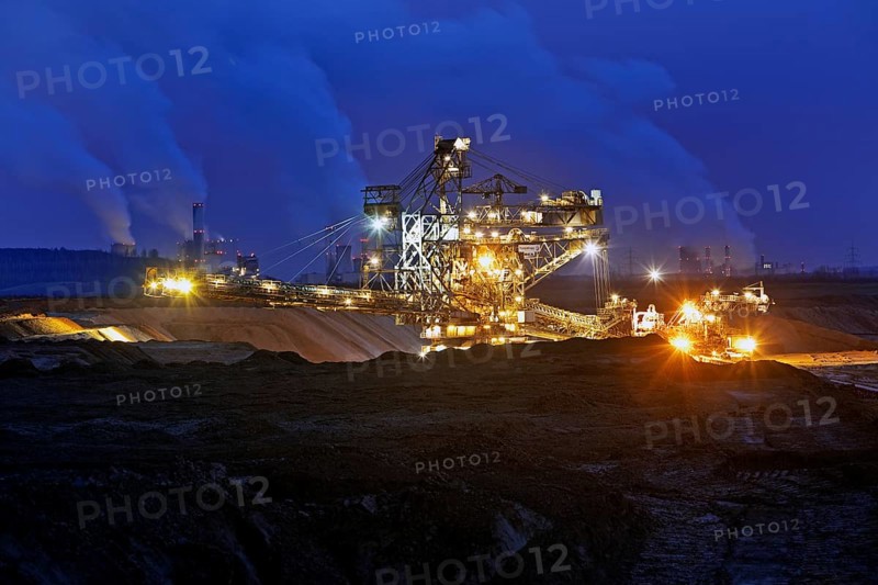 Opencast lignite mine with stacker and power plants in the evening