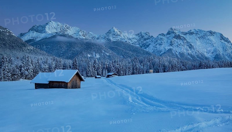 Winterly hummock meadows with hay barn and Karwendel mountains at dusk