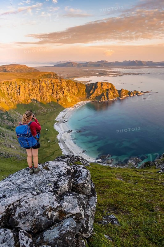 Hiker standing on a rocky outcrop overlooking beach and sea