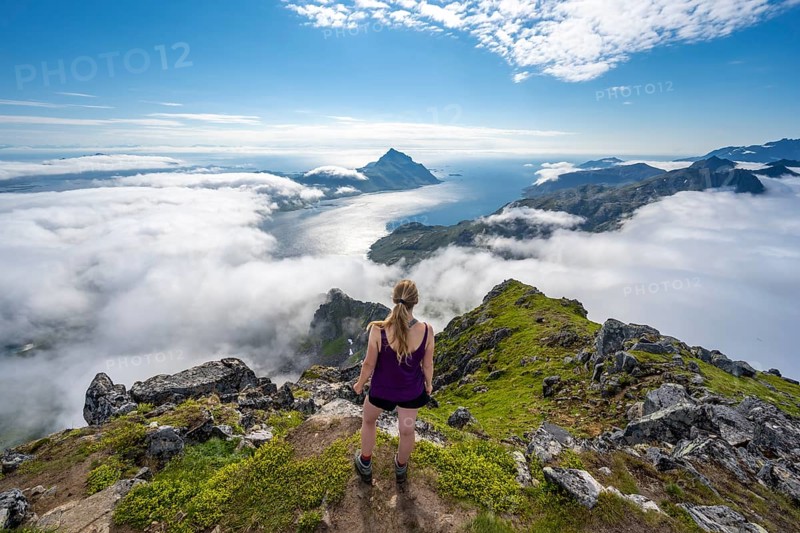 Hiker looking over mountain landscape in clouds