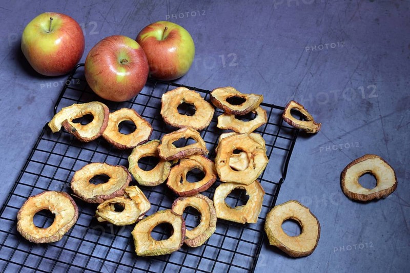 Dried apple rings on grate and apples