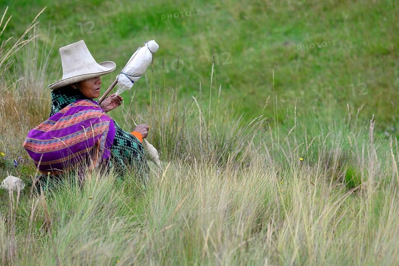 Indigenous woman sitting in the meadow spinning wool