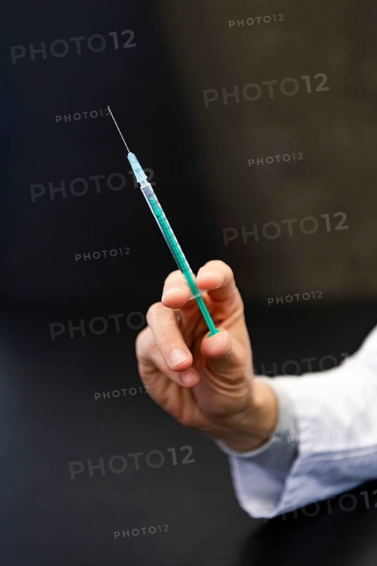 A hand holds a syringe for vaccine against COVID-19 at a vaccination center in Erding