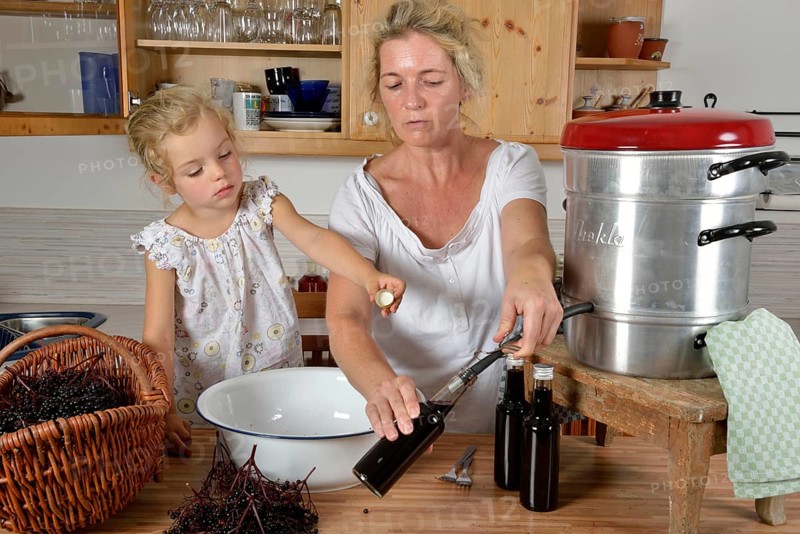 Woman and girl cooking elderberry juice