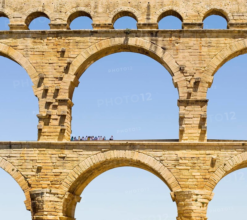 A group of tourists resting in the shadow of the Pont du Gard