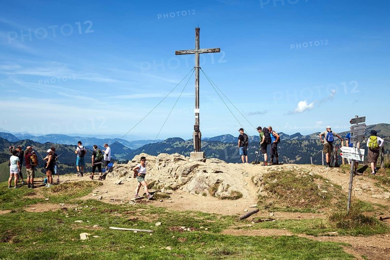 Hiker at the summit cross at Riedberger Horn