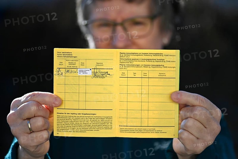 Woman proudly showing her vaccination certificate after being vaccinated with AstraZeneca against Covid-19