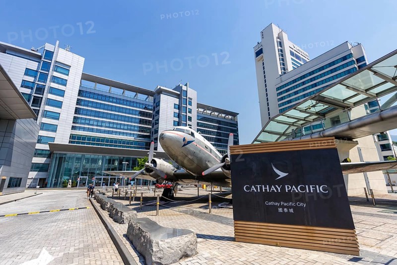 A Douglas DC-3 aircraft with registration VR-HDA in front of Cathay Pacific City at Hong Kong Airport
