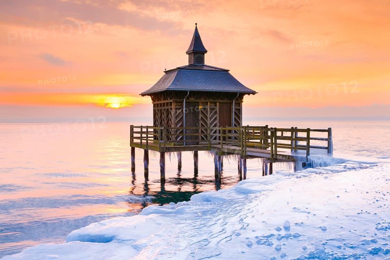 Iced wooden bathhouse at sunrise on Lake Neuchatel in Gorgier