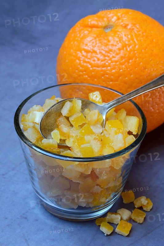 Candied orange peel cubes in glass with spoon