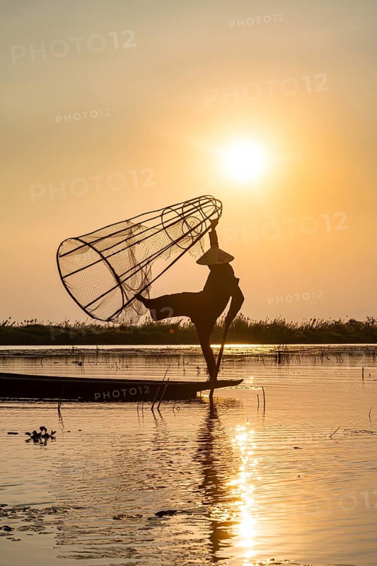 Fisherman at Inle Lake with traditional Intha conical net at sunset