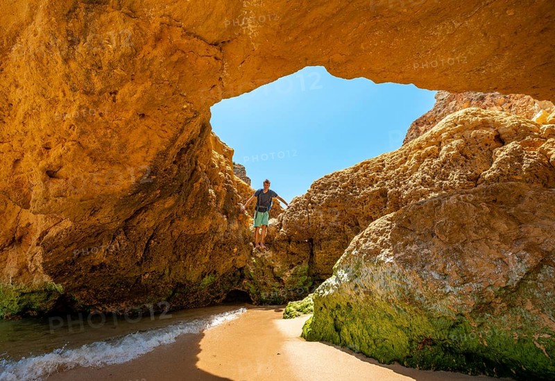 Young man standing in a rock cave with hole