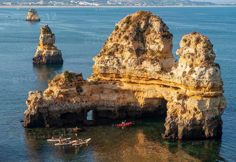 Kayakers paddling around rock formations in the sea