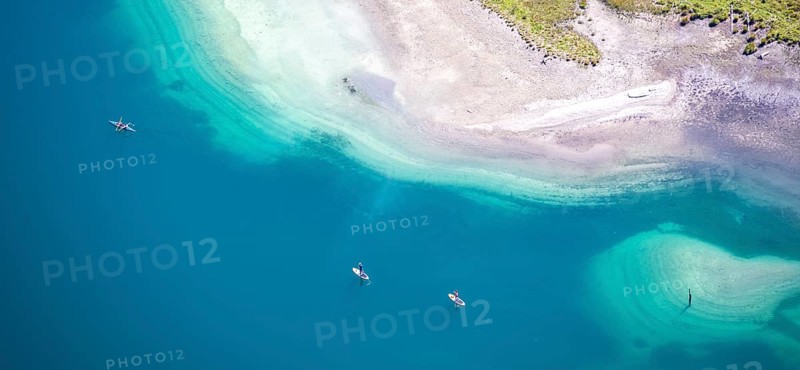People on a stand-up paddle and kayak on the shore of Plansee
