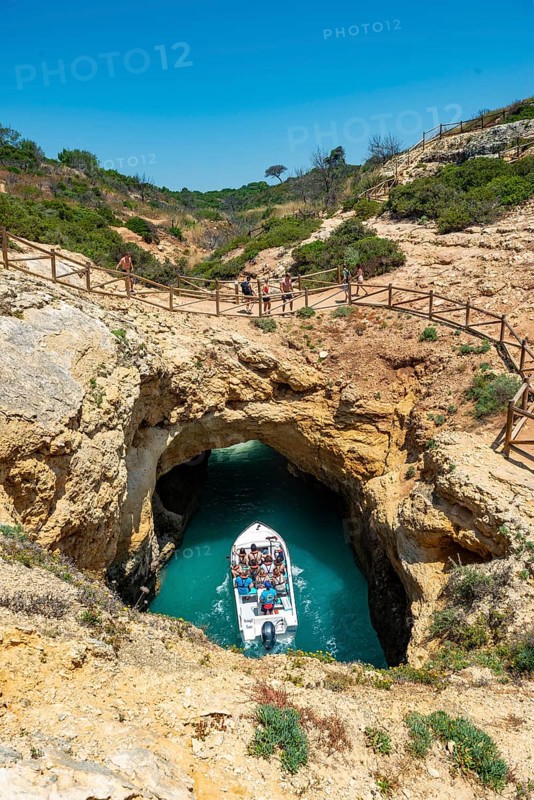 Excursion boat in the turquoise sea passes through rock caves and rock arches
