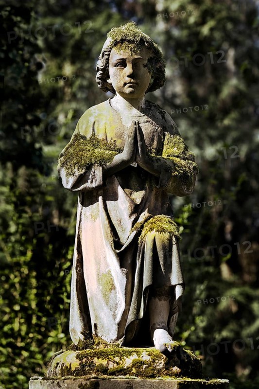Praying grave sculpture with moss at Melaten cemetery
