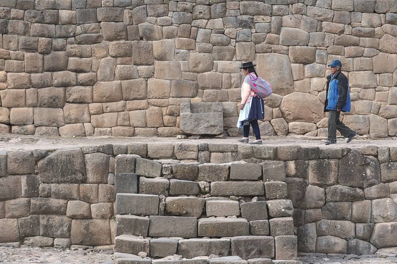 Old indigenous couple walking on the ruins of the Inca Temple of the Sun