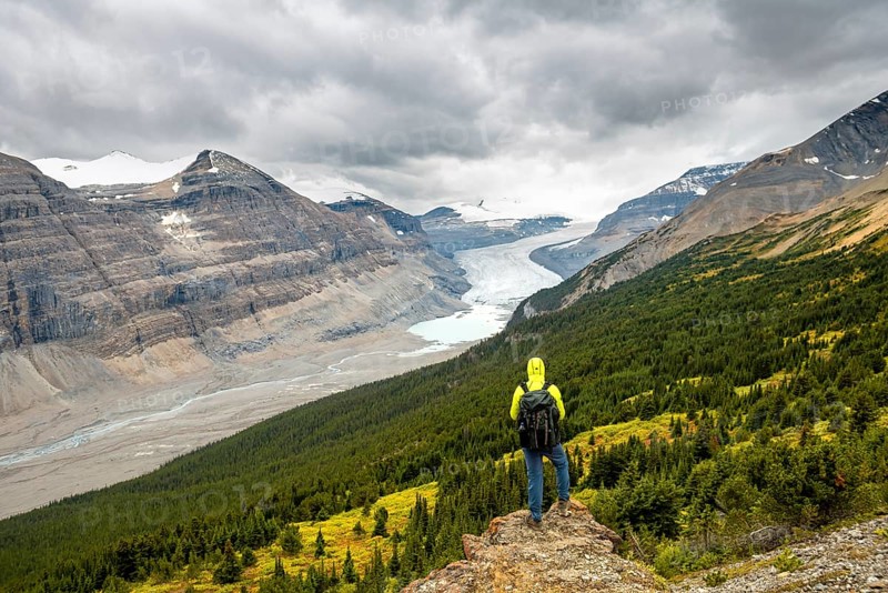 Hiker standing on rocks overlooking valley with glacier tongue