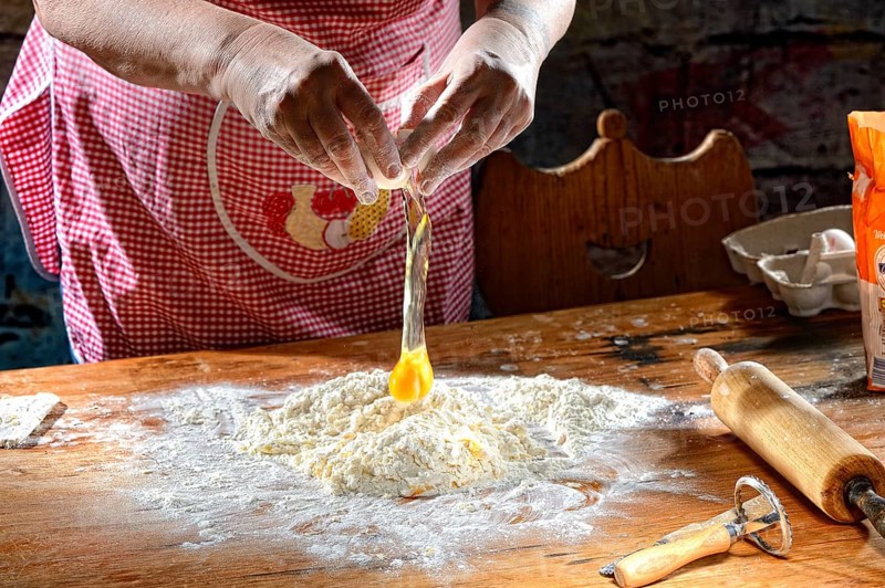 Cook making pasta dough on wooden table