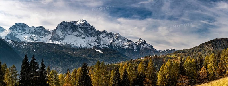 Snowy mountain peaks of the Civetta group with autumn lark forest in the foreground