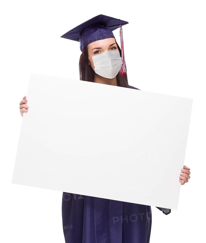 Graduating female wearing medical face mask and cap and gown holding blank poster board isolated on a white background