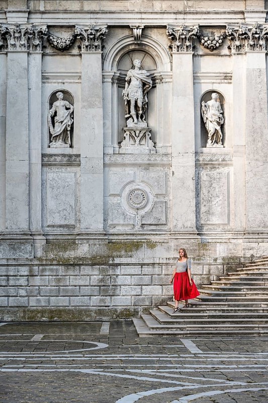 Young woman with red dress in front of white church