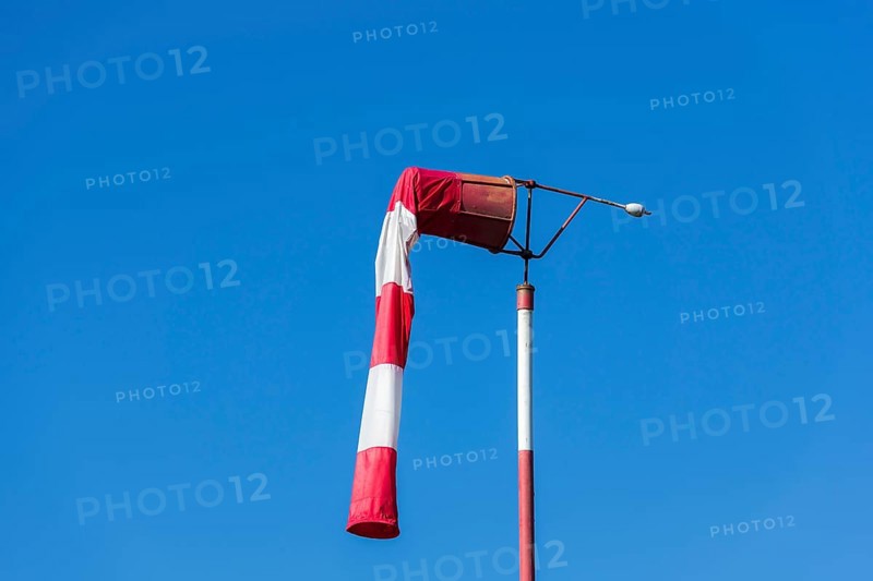 Red and white windsock against blue sky