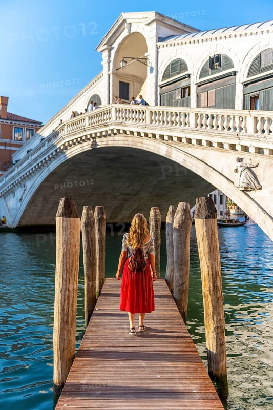 Young woman with red dress at a pier with boats