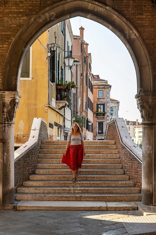 Young woman with red skirt walks through archway