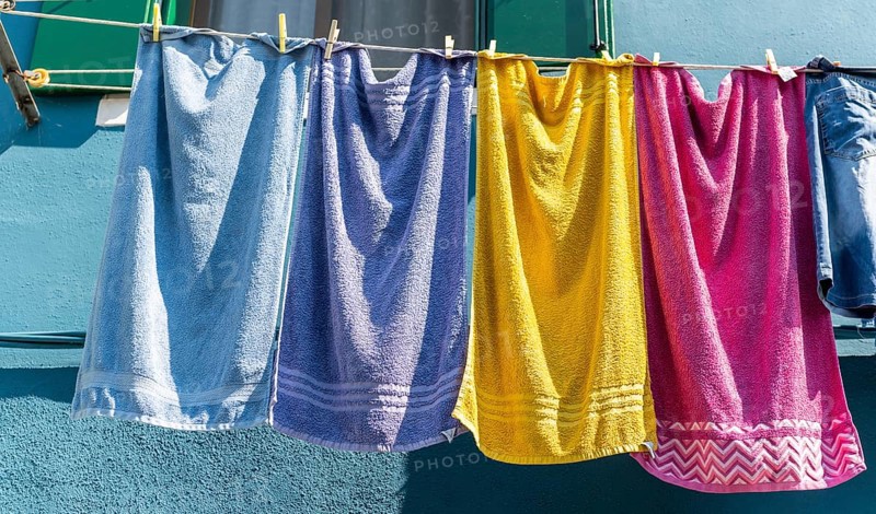 Colorful laundry on clothesline in front of blue house wall