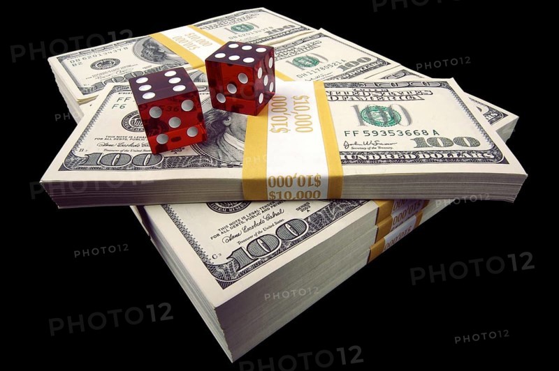 Stack of ten thousand dollar piles of one hundred dollar bills & dice on a black backgro