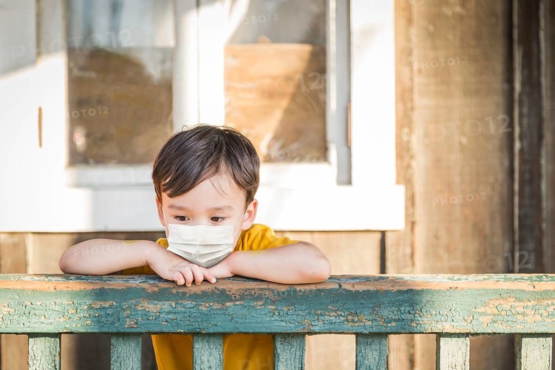 Young Mixed Race Chinese and Caucasian Boy Playing Alone Wearing Medical Face Mask Outside