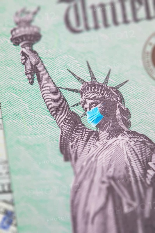 United states IRS stimulus check with statue of liberty wearing medical face mask