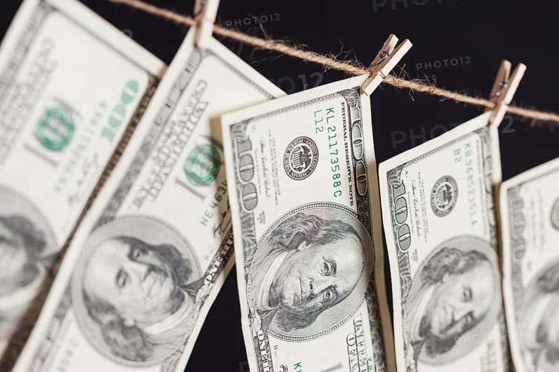 Hundred dollar bills hanging from a clothesline on a dark background