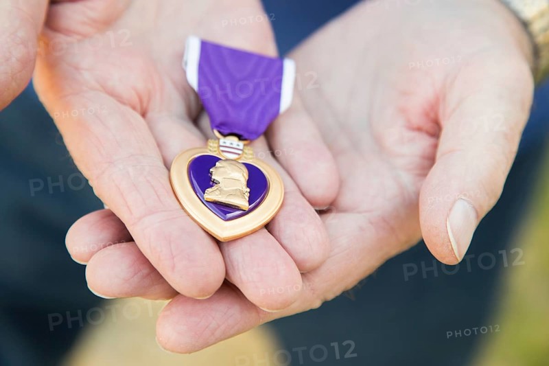 Senior man holding the United States military purple heart medal in his hands