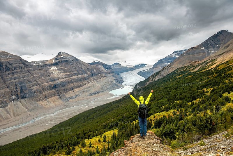 Hiker standing on rocks overlooking valley with glacier tongue