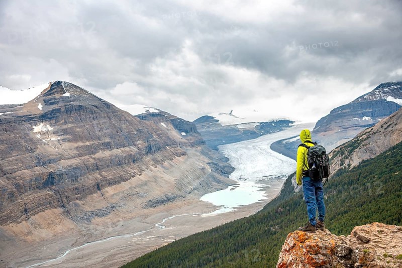 Hiker standing on rocks overlooking valley with glacier tongue