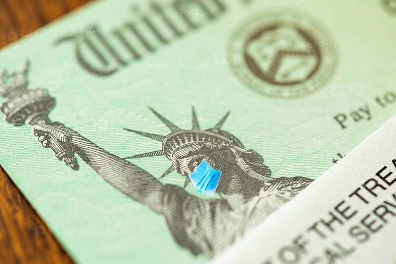 United states IRS stimulus check with statue of liberty wearing medical face mask