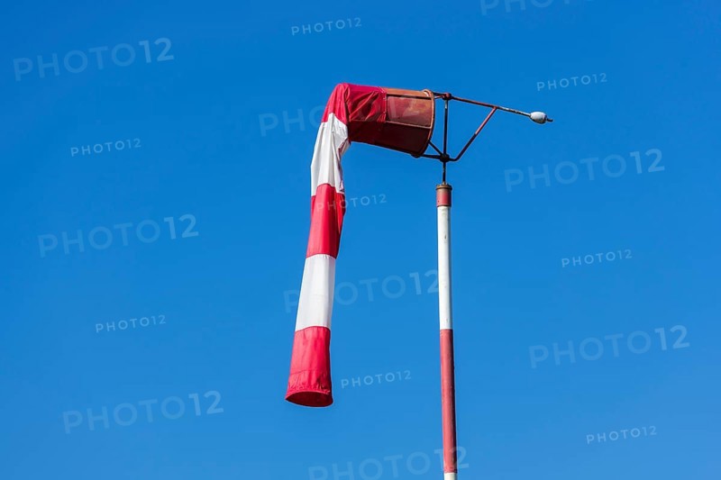 Red and white windsock against blue sky